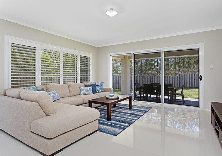 Living room in SIL home 1, with a corner sofa and glass doors opening to the outdoor seating area