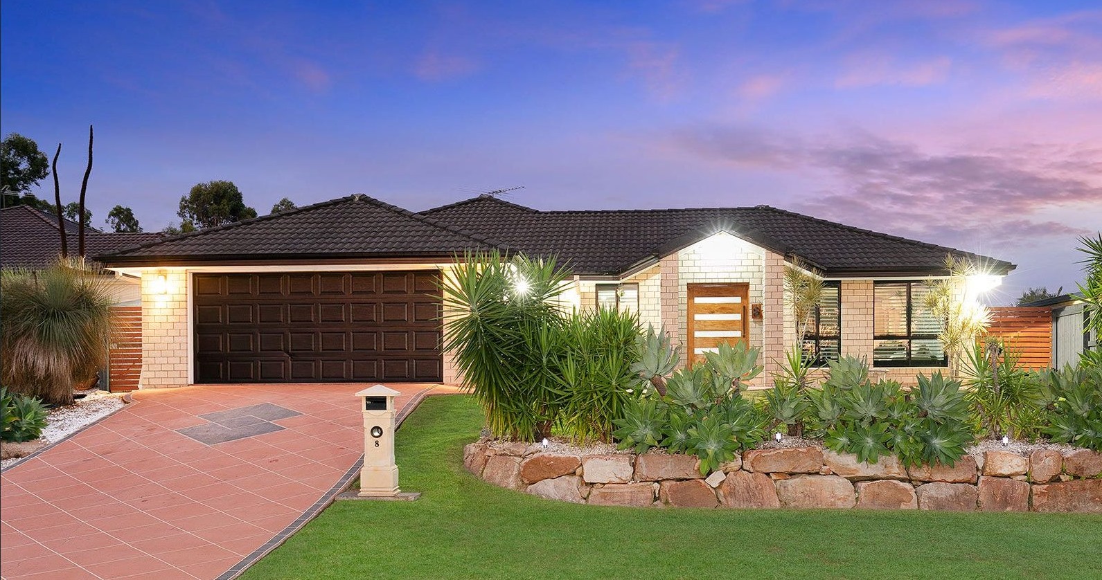 Front of SIL home 2 at dusk, with a brick facade, double garage and landscaped garden