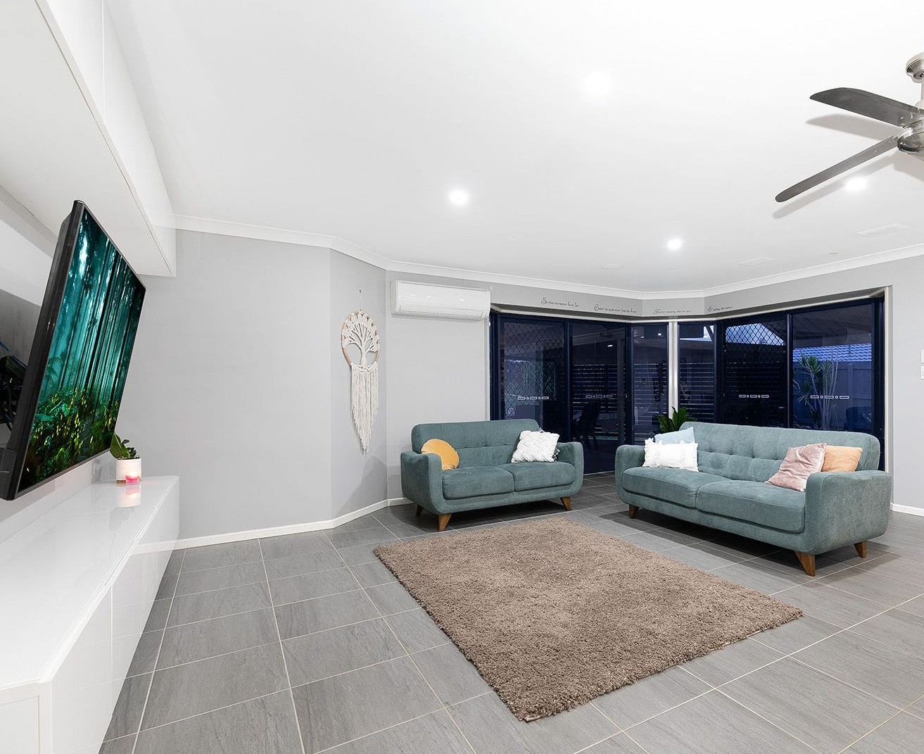 Living room in SIL home 2, with two green sofas, a television and sliding doors to the outdoor area