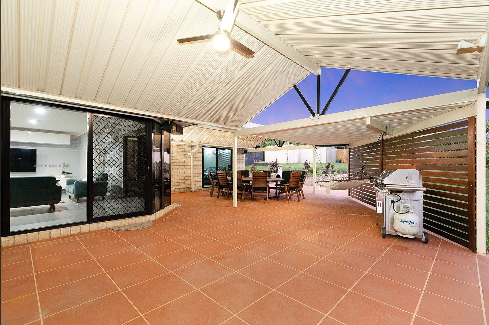 Covered outdoor area at SIL home 2, with a dining table, hammock, barbecue and ceiling fan